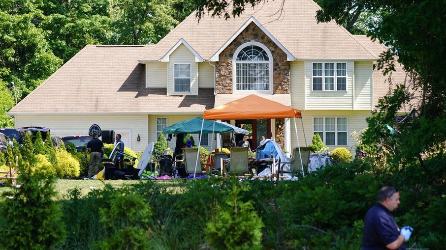 Casa em Nova Jersey onde aconteceu a festa e o tiroteio; policiais investigam o local na manhã de domingo (23)/Matt Rourke/AP Photo
