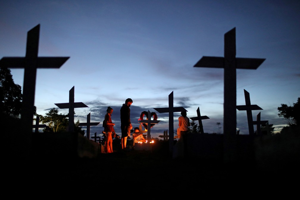 Parentes rezam sobre o túmulo de ente querido morto pela Covid/Bruno Kelly/Reuters