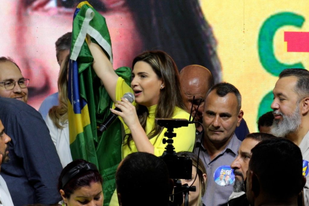 Com a bandeira do Brasil numa das mãos, Clarissa discursa ao lado do presidente do diretório estadual do União Brasil, Waguinho, e de outros aliados de sua candidatura/Divulgação